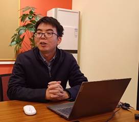 桌子上放着笔记本电脑前的人描述已自动生成